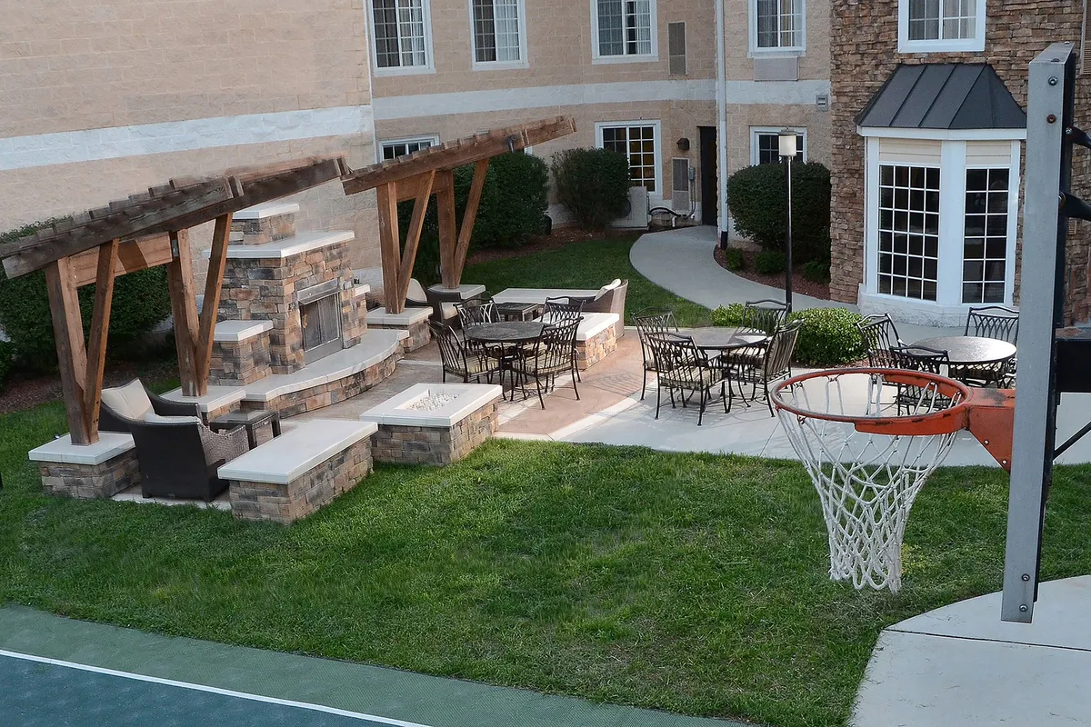 An inviting exterior space featuring a stone fireplace, seating area, and a basketball hoop. The area is designed for outdoor gatherings, barbecues, and recreational activities, adding a dynamic and social element to the property.